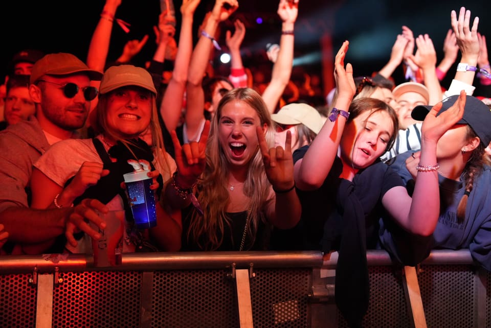 Menschen jubeln bei einem Konzert hinter einer Absperrung am Open Air Lumnezia 2024.