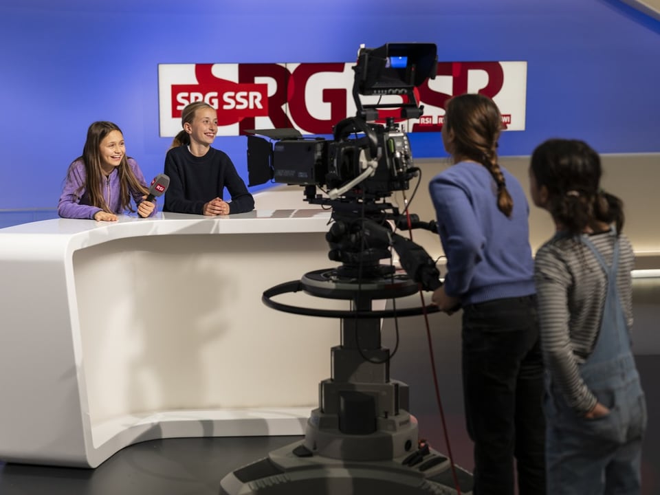 Kinder moderieren Nachrichtensendung im Fernsehstudio.