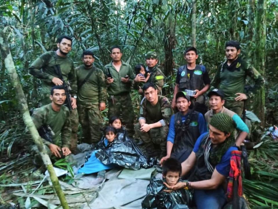 Rettungskräfte posieren gemeinsam mit den geretteten Kinder im Dschungel