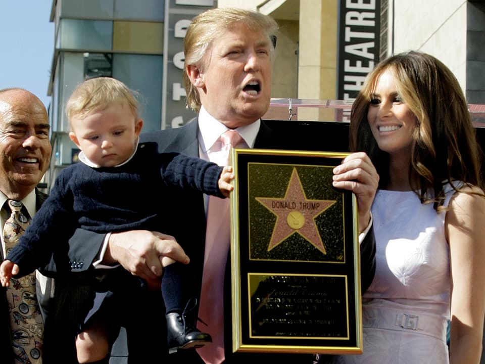 Donald Trump hält im rechten Arm ein Baby – in der linken Hand die Urkunde für den Stern auf dem Walk of Fame.