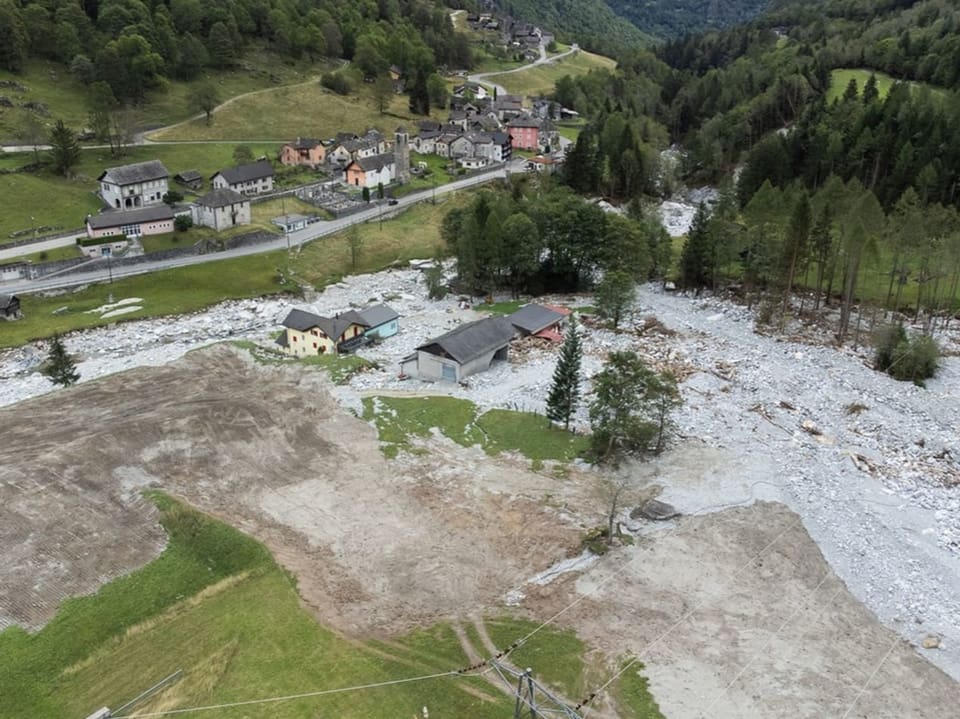 Luftbild von einem Dorf in den Bergen mit Geröllfeld.