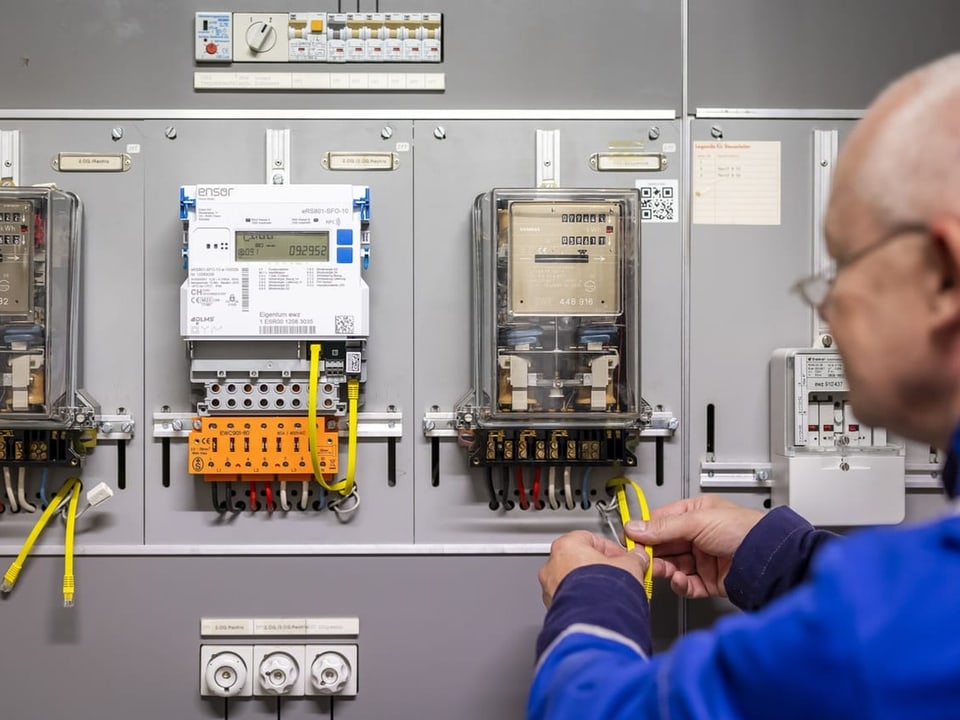 Ein Zaehlermonteur im Auftrag der EWZ installiert einen Smart Meter-Stromzaehler, Mitte, neben einem alten Stromzaehler 