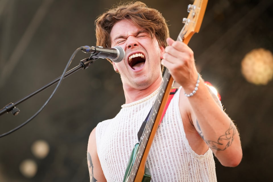 Sänger und Bassist Alexander Bratschi beim Singen auf der Bühne am Open Air Lumnezia 2024.