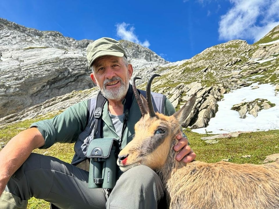 Bärtiger Jäger vor Bergpanorama mit geschossener Gämse.