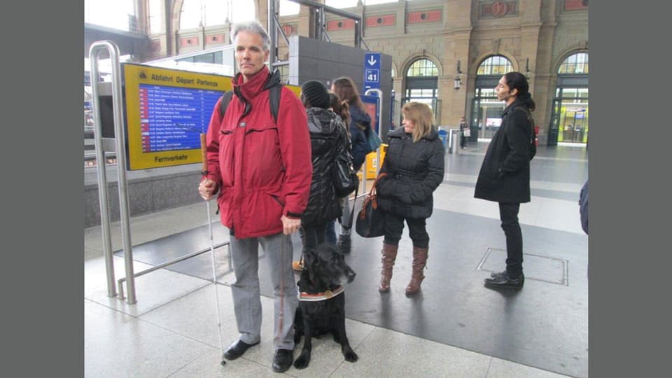 Mann mit Blindenstock und Blindenhund im Zürcher Hauptbahnhof.
