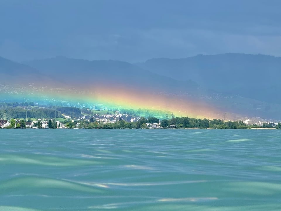 Flacher Regenbogen über dem Wasser.