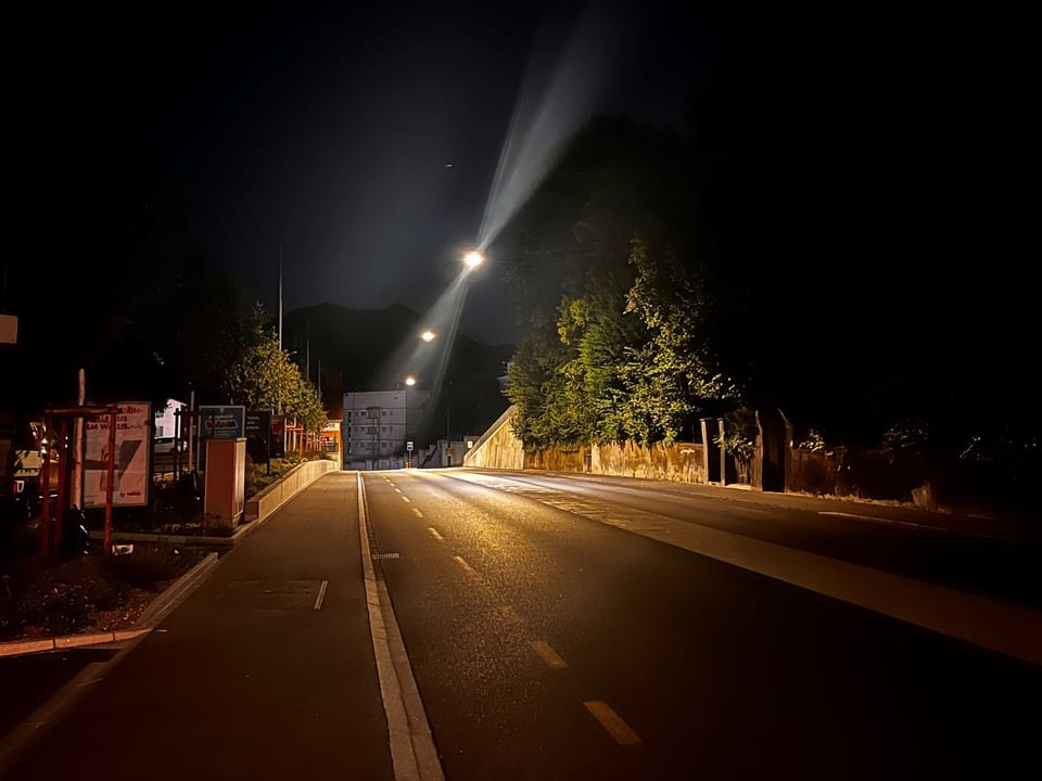 Eine Strasse bei Nacht, Strassenlampen beleuchten den Weg. 