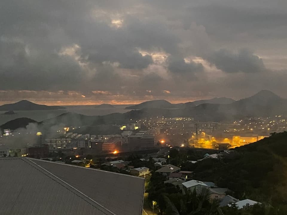 Stadt bei Sonnenuntergang mit Bergen im Hintergrund.
