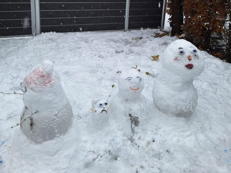 Vier Schneemänner mit farbigen Gesichtern.