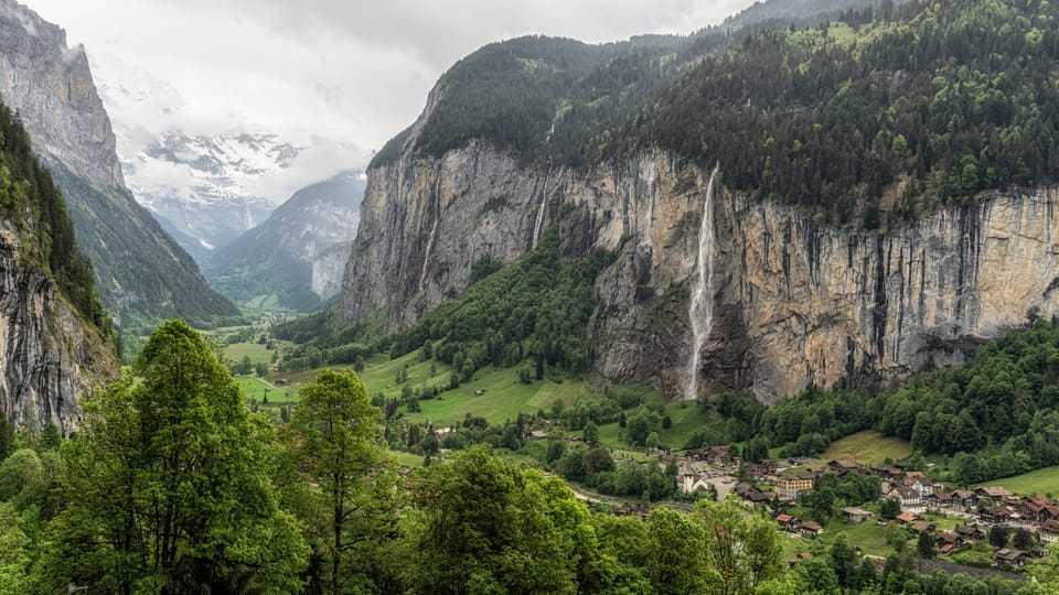 Landschaftspanorama im Lauterbrunnental mit Wasserfall und Dorf.