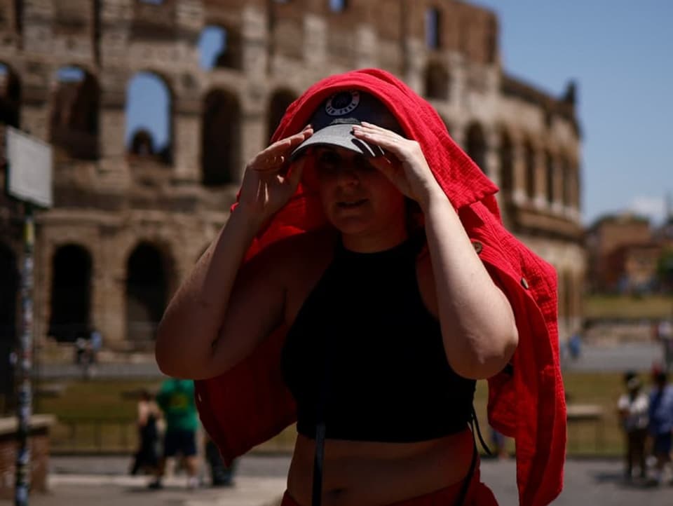 Eine Frau vor dem Kolosseum in Rom sucht Schutz vor der Sonne.