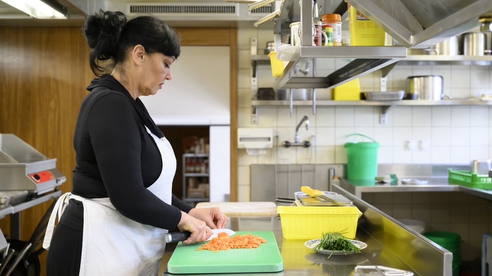 Frau schneidet Karotten in Restaurantküche