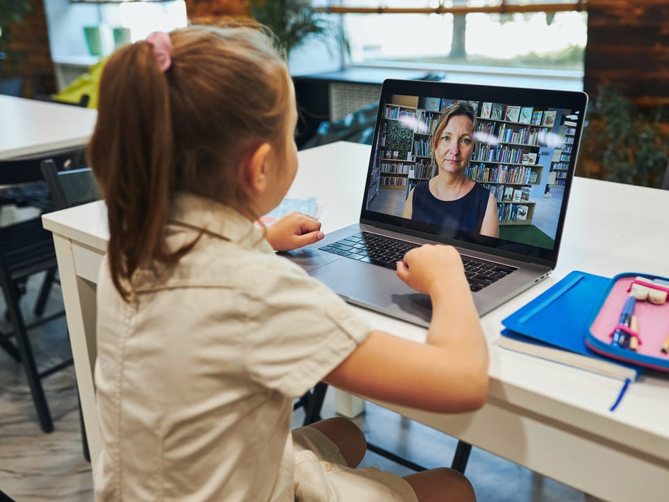 Mädchen bei Videokonferenz mit Frau auf Laptop.