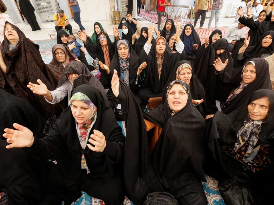 Frauen in religiöser Kleidung beten draussen.