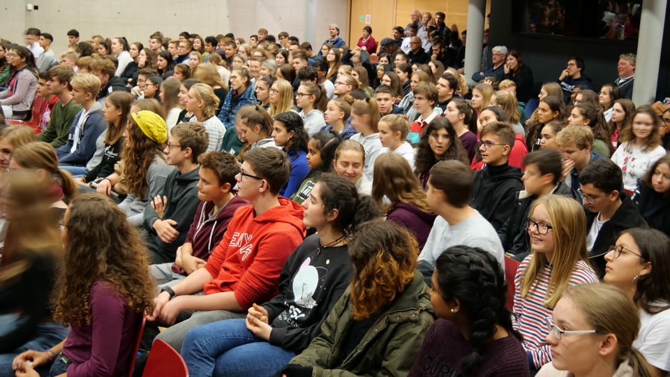 Junge Frauen und Männer versammelt in einem grossen Saal