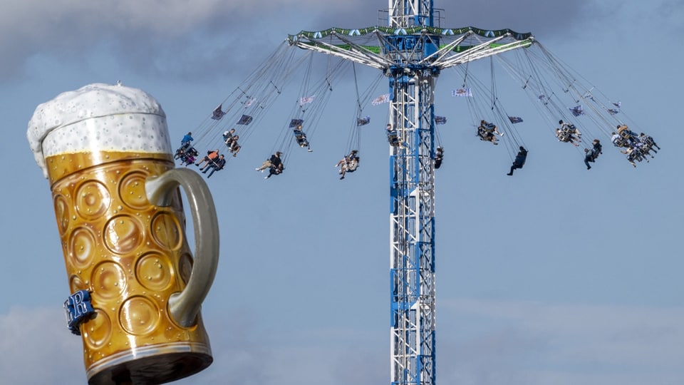 Riesenrad mit Menschen und grosses Bierkrug-Schild im Vordergrund.