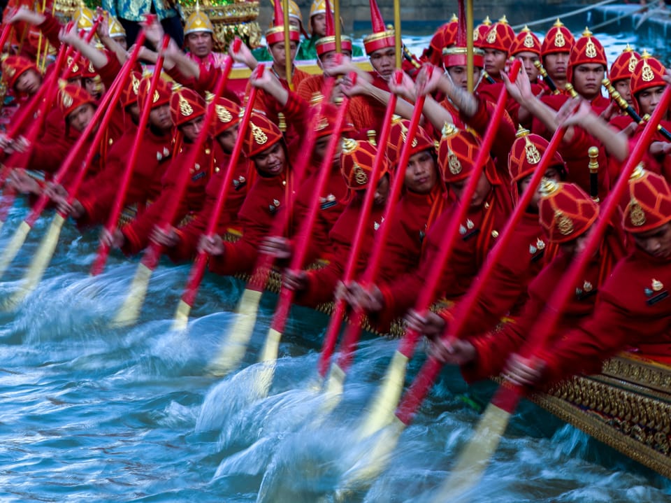 Ruderer in roten Uniformen bei traditionellem Bootsrennen auf dem Wasser.