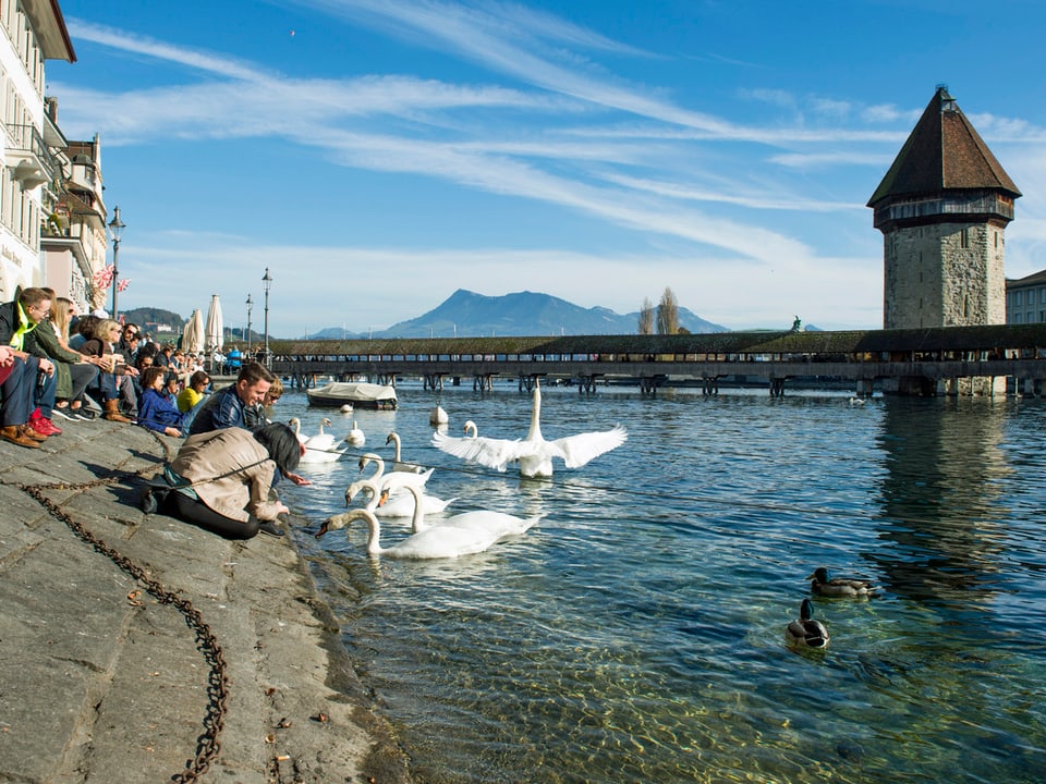 Einheimische und Touristen geniessen das sonnige Herbstwetter an der Reuss in Luzern. (keystone)