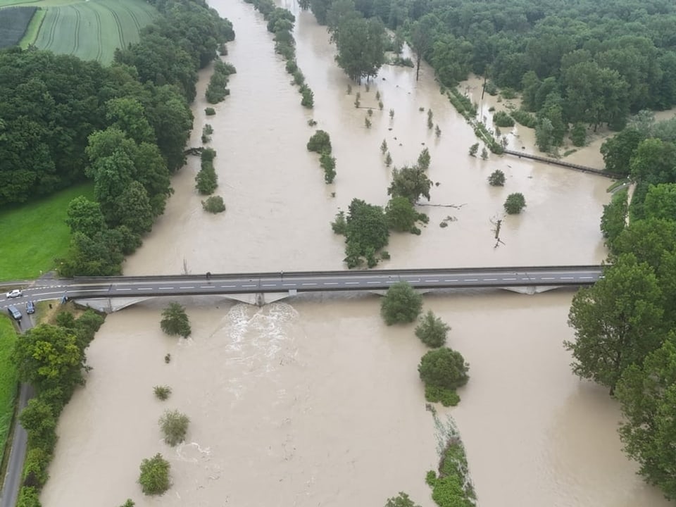 Luftaufnahme eines überschwemmten Flusses mit Brücke.