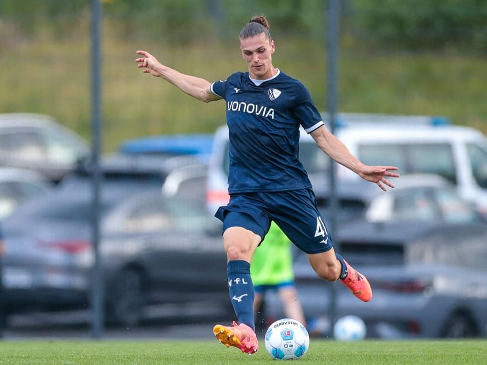 Fussballspieler in blauem Trikot beim Schuss auf dem Spielfeld.