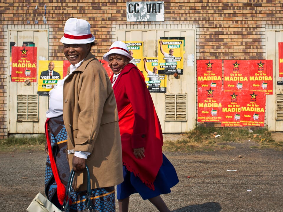 Zwei Südafrikaner unterwegs in einem Township von Johannesburg. Im Hintergrund Wahlplakate.