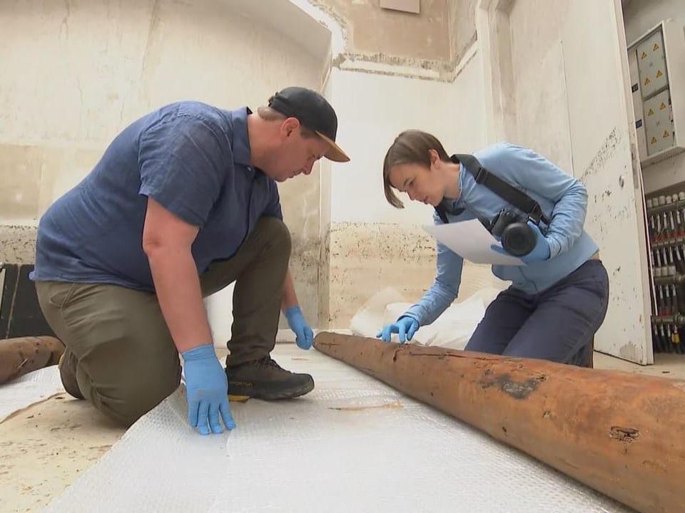 Zwei Archäologen knien über einem Stück Holz