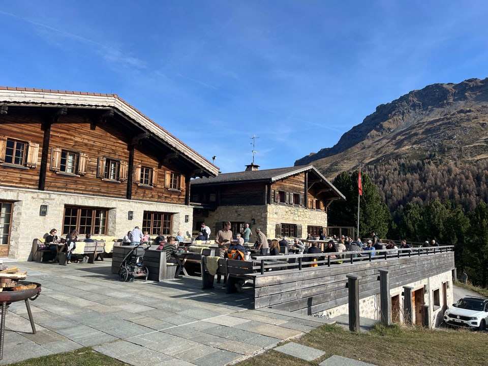 Terrasse eines Bergrestaurants mit Gästen und Bergblick.