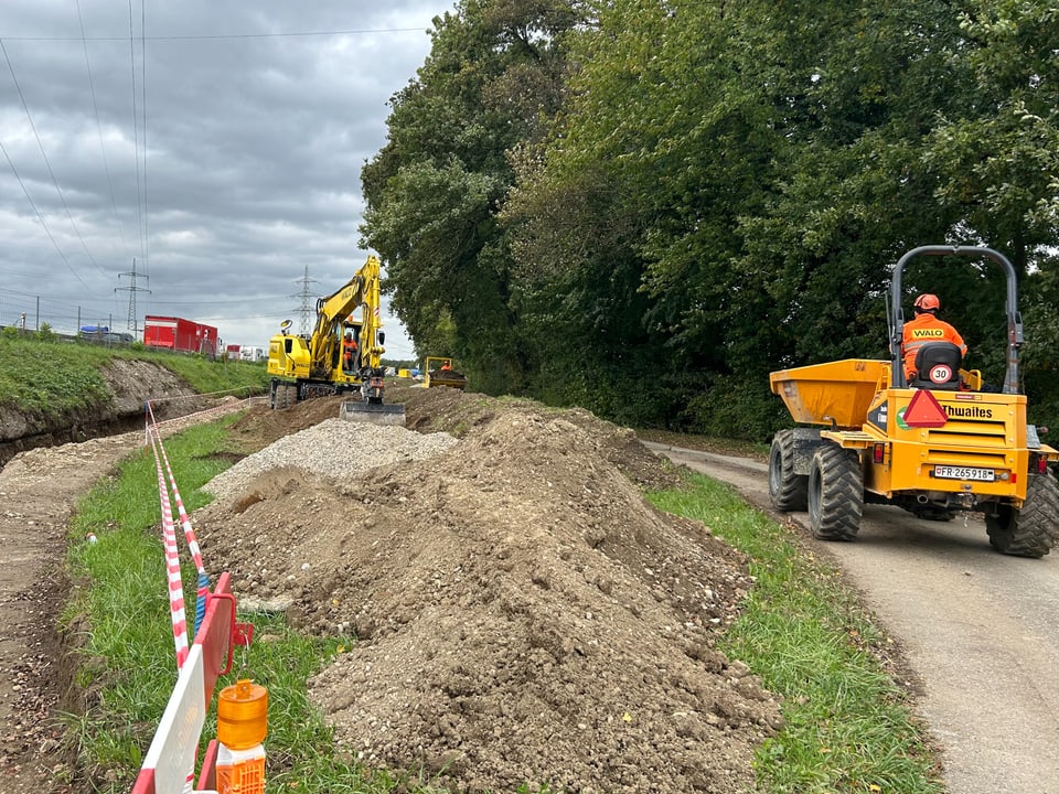 Baustelle mit Bagger und Muldenkipper auf einer Strasse.