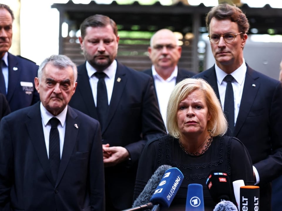 Politiker vor Mikrofonen bei einer Pressekonferenz.