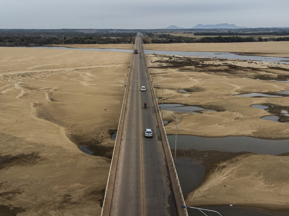 Luftaufnahme von Fahrzeugen auf einer Brücke über eine trockene Landschaft.