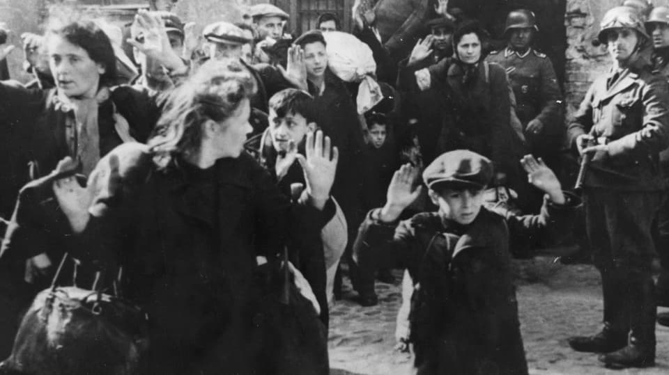 Schwarz-weiss-Foto: Jüdinnen und Juden mit erhobenen Händen.
