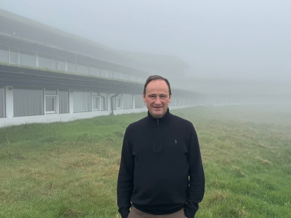 Mann steht vor einem Gebäude im Nebel.