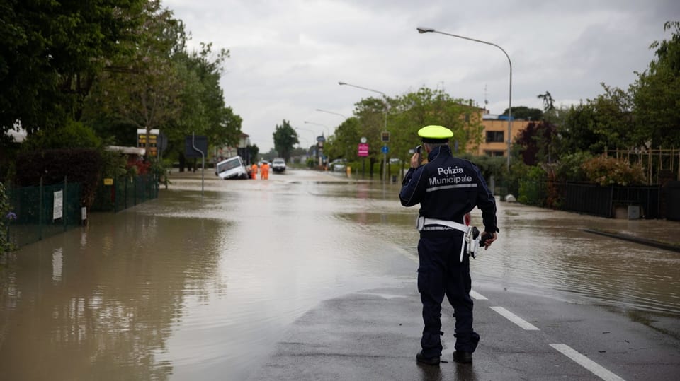 Ein Polizist vor einer überfluteten Strasse.