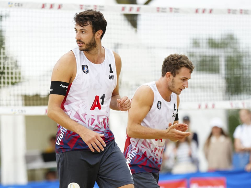 Zwei Männer spielen Beachvolleyball.