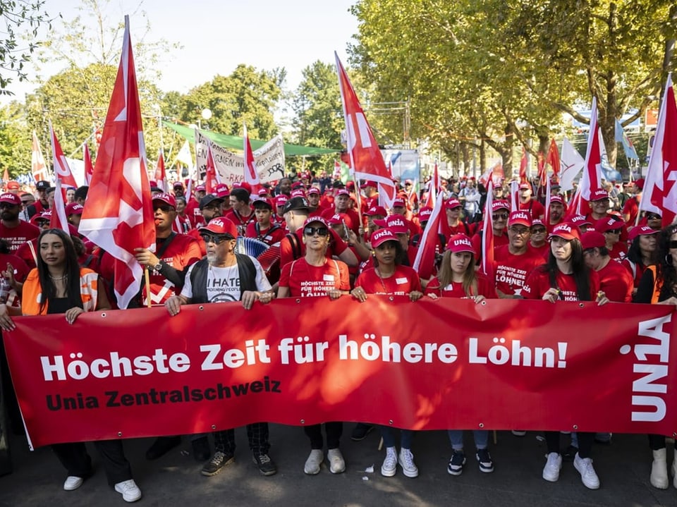 Demonstration mit rotem Banner 'Höchste Zeit für höhere Löhne!' und Unia-Flaggen