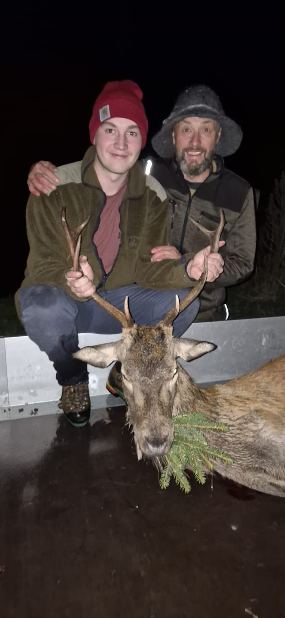 Zwei Männer posieren mit einem erlegten Hirsch.