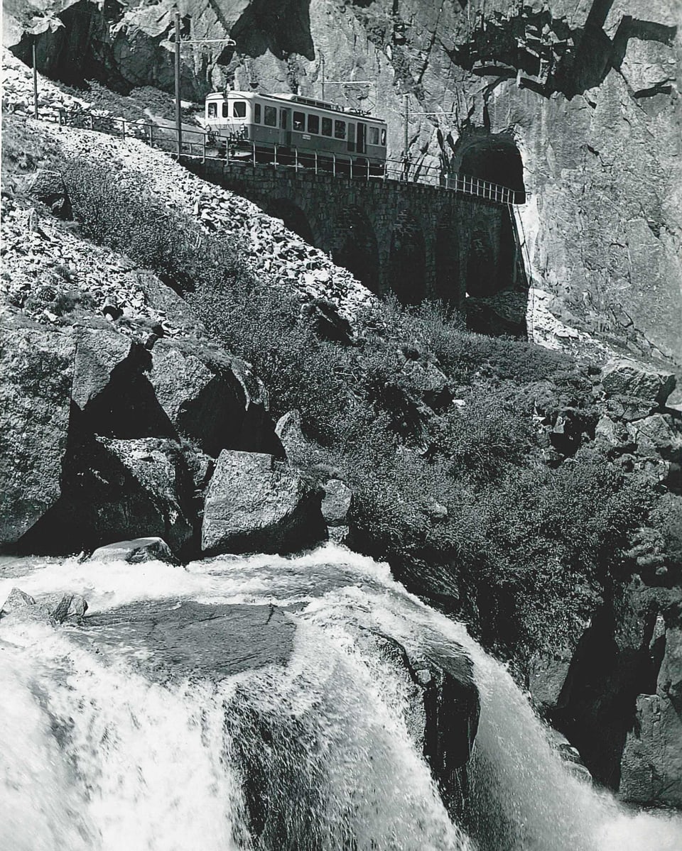 Historische Schwarzweiss-Aufnahme einer alten Eisenbahnbrücke mit kurzer Zugkomposition.