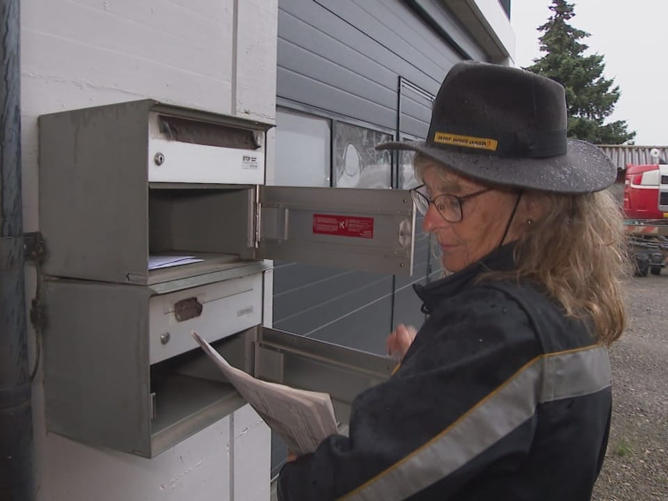 Frau beim Öffnen von Briefkästen.