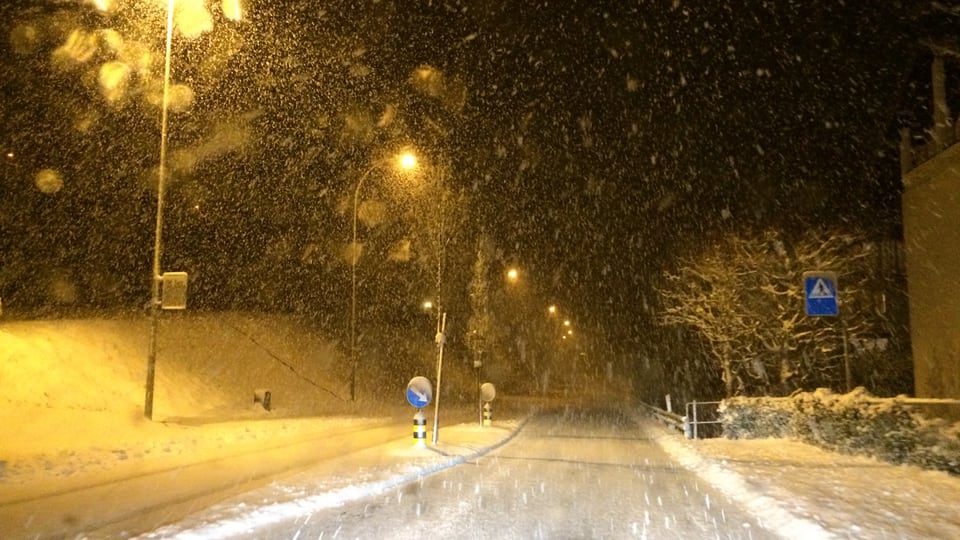 Schneefall in der Nacht, die Strasse ist schneebedeckt.