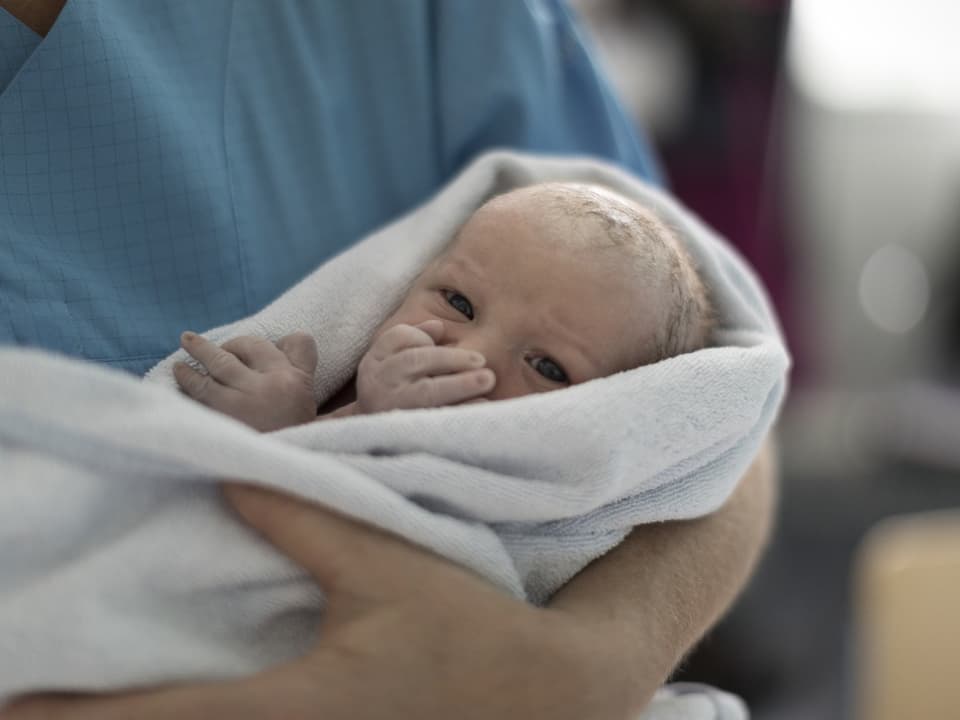 Neugeborenes Baby in einer Decke gehalten.