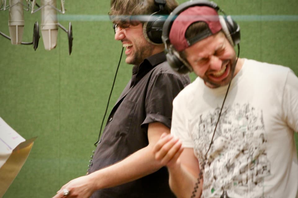 Zwei Männer lachen während der Tonaufnahmen.