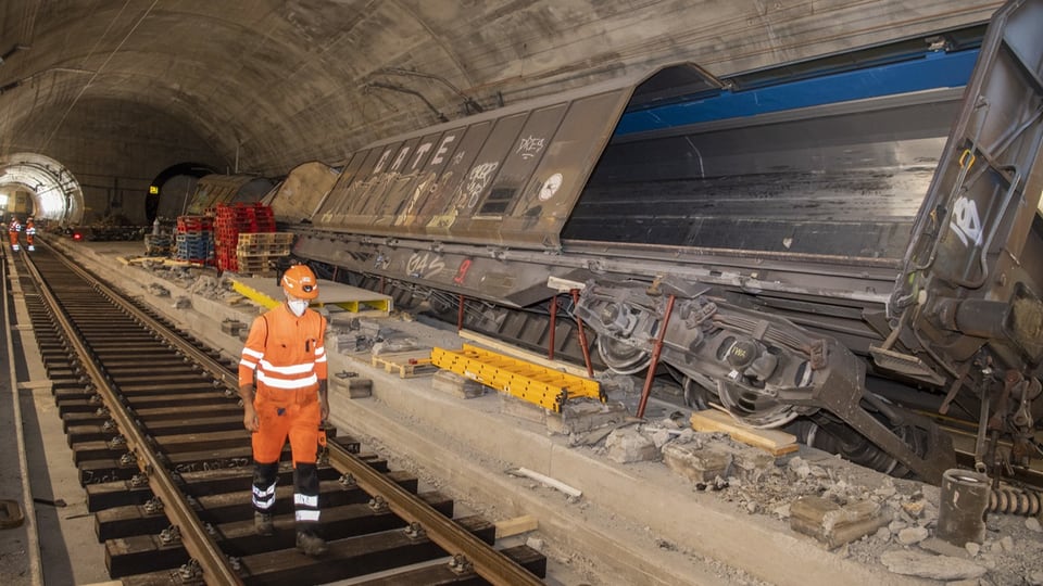 Arbeiter untersucht entgleisten Güterwagen in einem Tunnel.