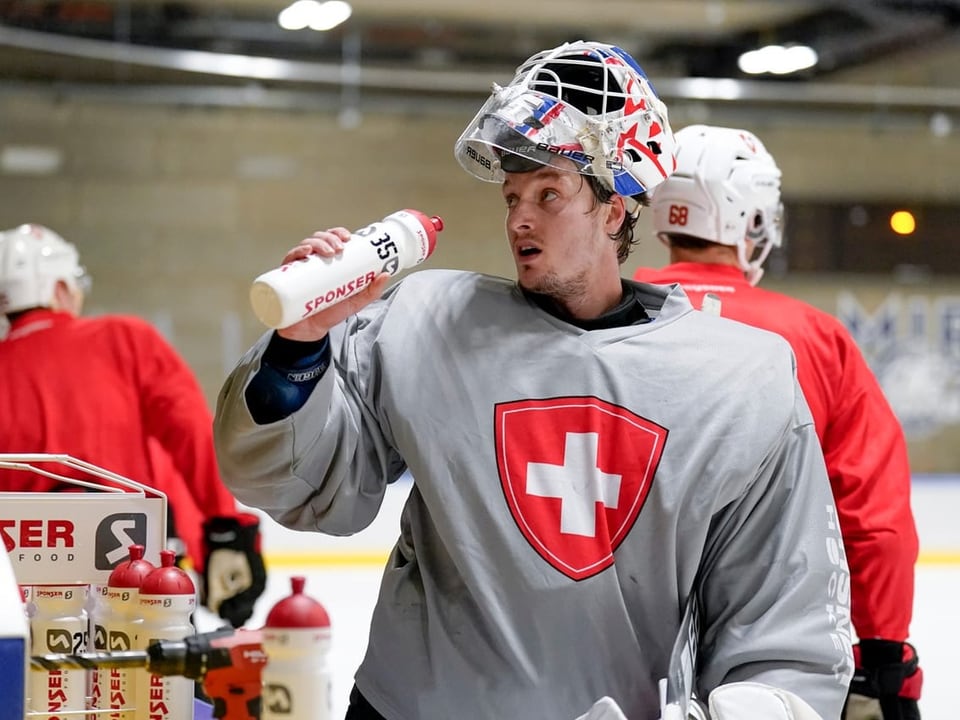 Eishockeyspieler in grauem Trikot mit Trinkflasche. 