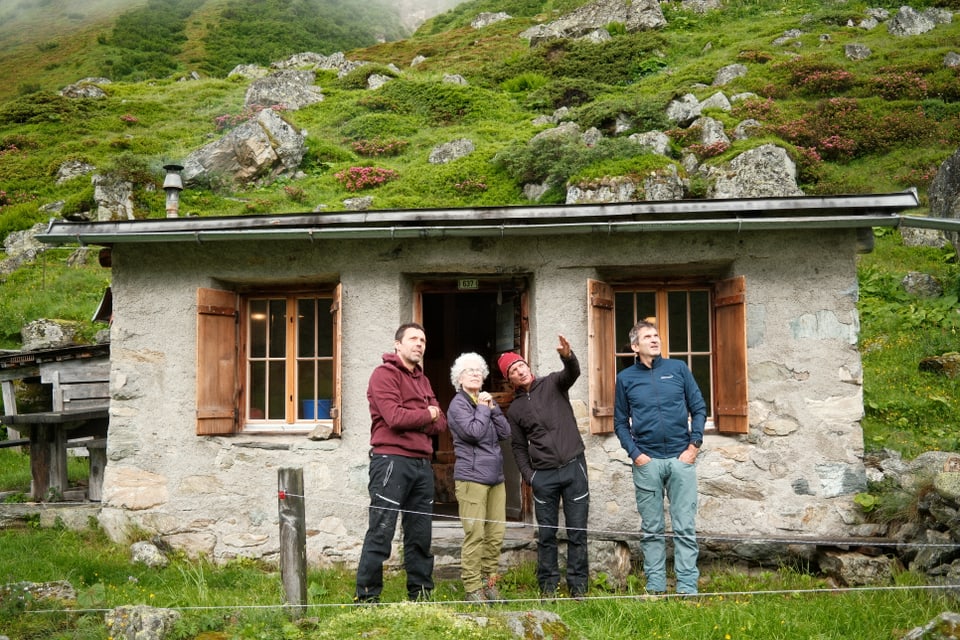 Vier Personen vor einer Berghütte.