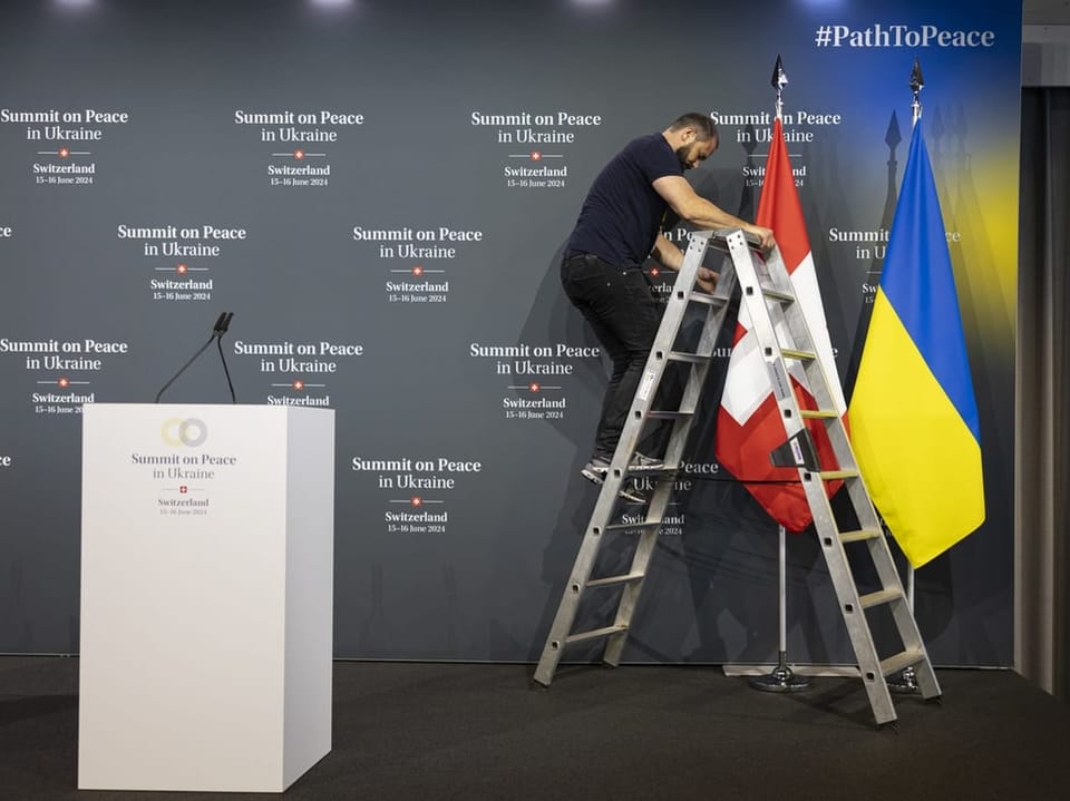 Ein Mann richtet eine Schweizer und eine ukrainische Flagge her. 
