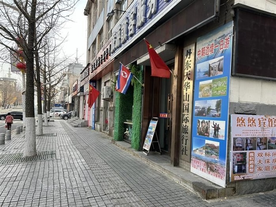 Strasse mit Gebäuden, Schildern und Flaggen vor Reisebüros.