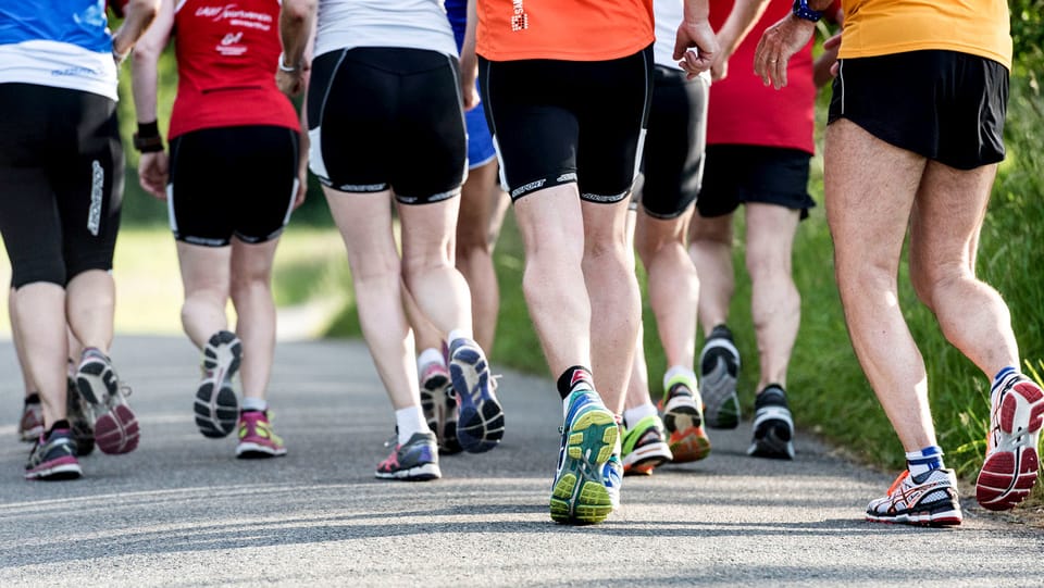 Beine von Joggern und Joggerinnen, die dicht beieinander laufen.