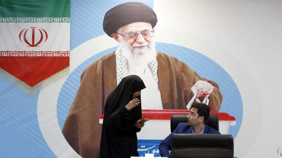 Ein Mann und eine Frau vor Bild von Ali Chamenei.