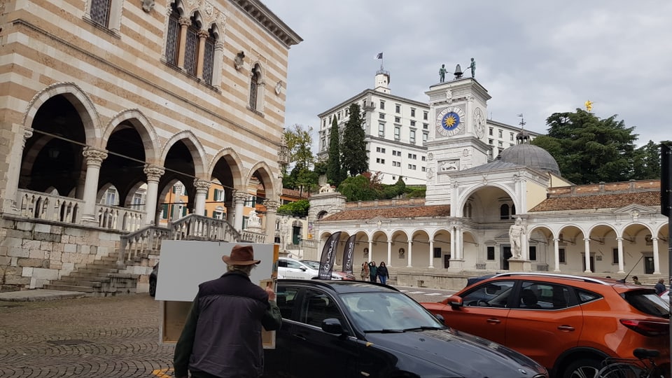 Maler vor historischem Gebäude und Turm mit Uhr in Udine.