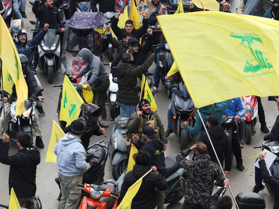 Demonstranten auf Motorrollern mit gelben Fahnen.